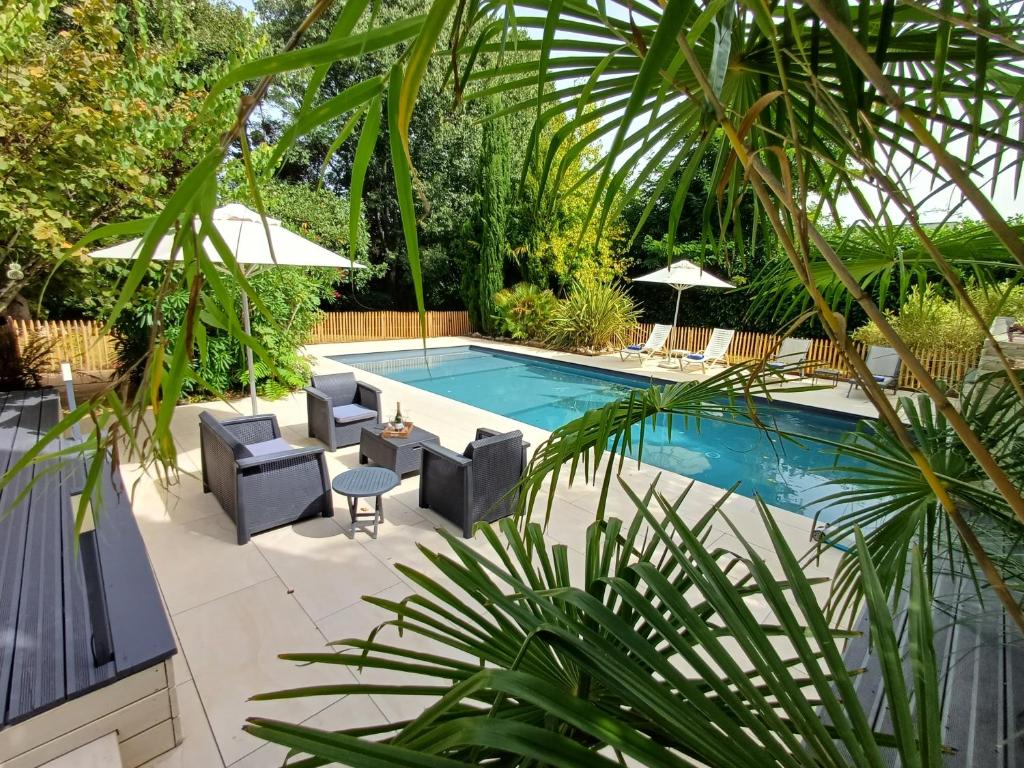 een zwembad in een tuin met stoelen en een tafel bij La Longère Bordeaux gite de charme prés de Bordeaux in Cénac