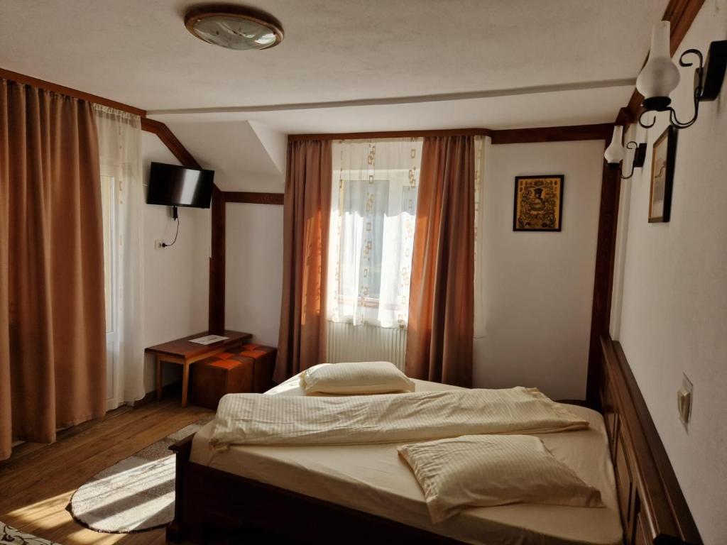 Pensiunea Cota 1200 Piscul Negru في أريفو: غرفة نوم بسرير مقابل نافذة