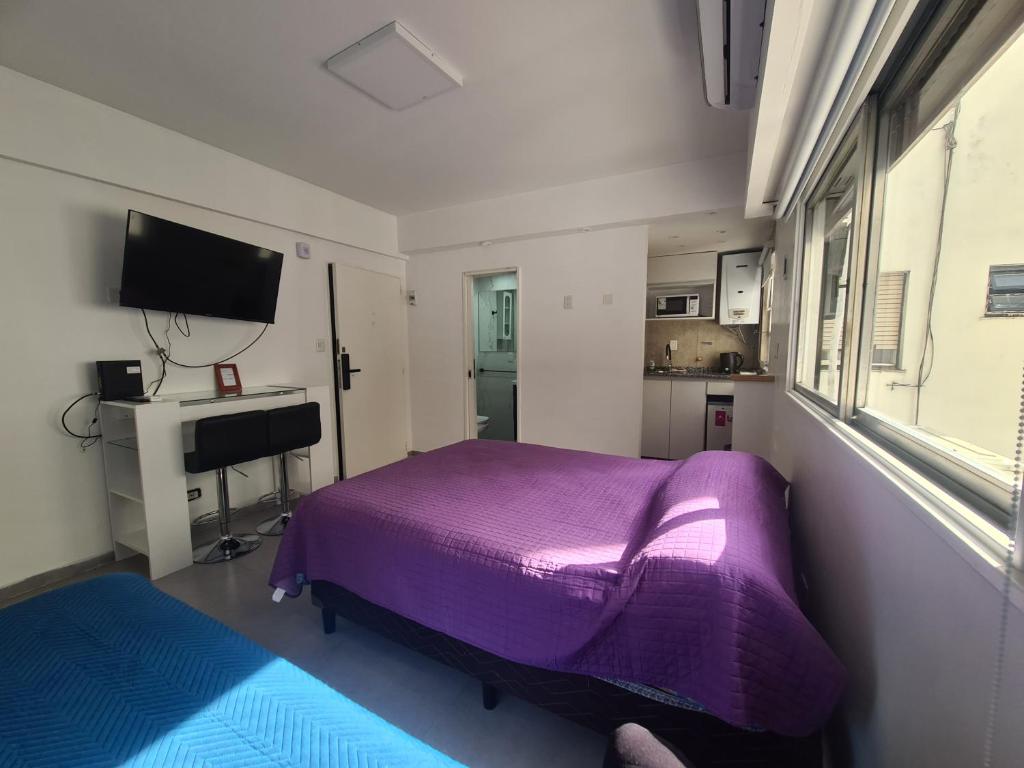 1 dormitorio con cama morada y escritorio en Av. Corrientes 1670 - Paseo La Plaza - en Buenos Aires