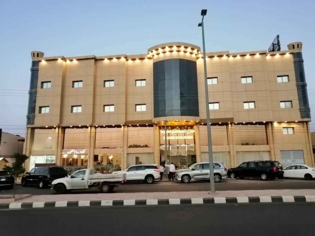 ein großes Gebäude mit Autos auf einem Parkplatz in der Unterkunft منازل الماسة للشقق المخدومـة in Ha'il