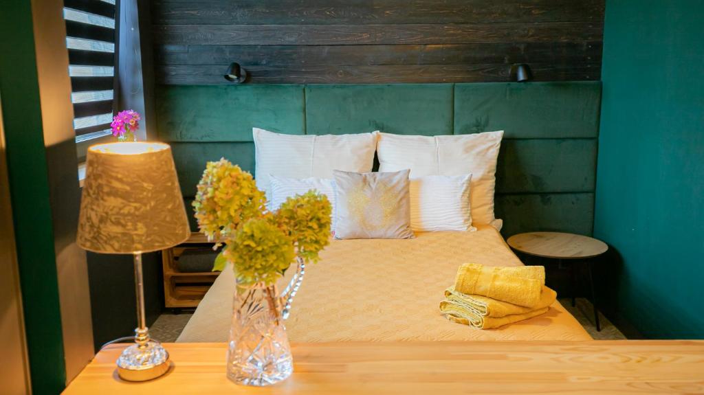 a bed with a vase of flowers on a table at Apartamenty Miejski Ogród in Bielsko-Biała