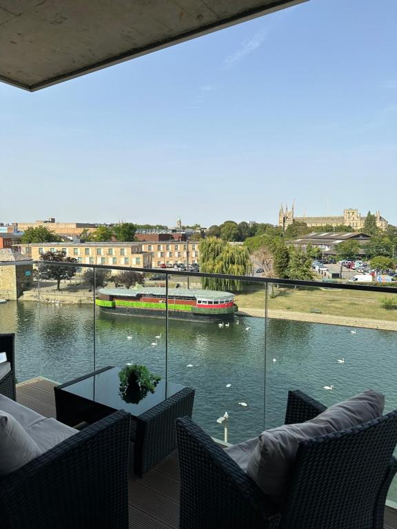 a balcony with a view of a river with a boat at Riverside Apartment in Peterborough