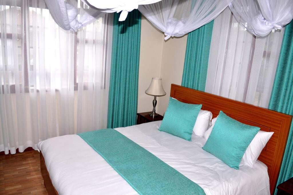 1 dormitorio con 1 cama con almohadas azules y blancas en Villa (2) Del Sol: Lakefront and Cruise Boat en Kisumu