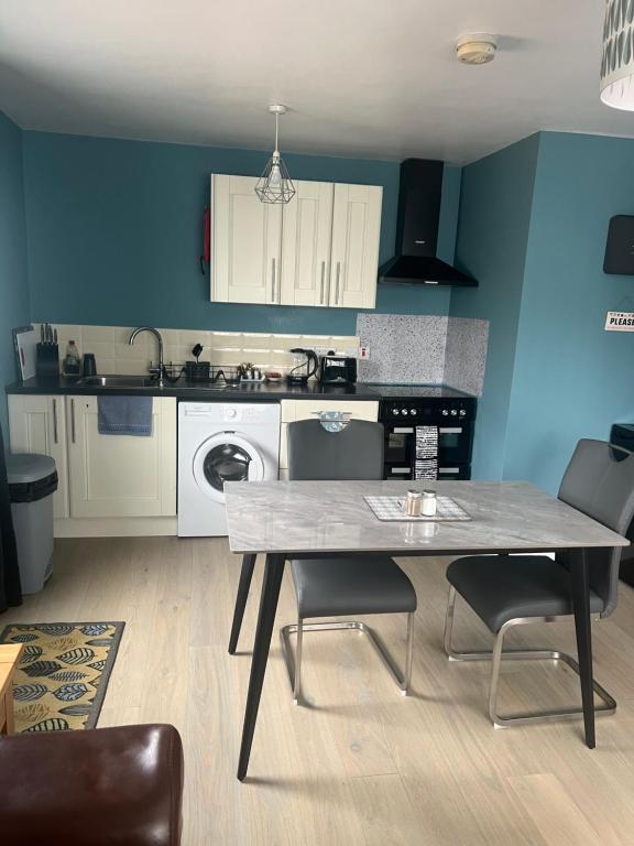 a kitchen with a table and chairs in a room at 'Kodi's Place' Well appointed 1 bedroom apartment with excellent transport links and free Wi-Fi in Whiteabbey