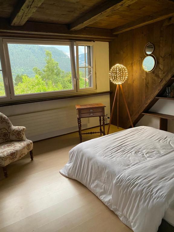 a bedroom with a bed and a chair and a window at La maison du petit bonheur in Moutier