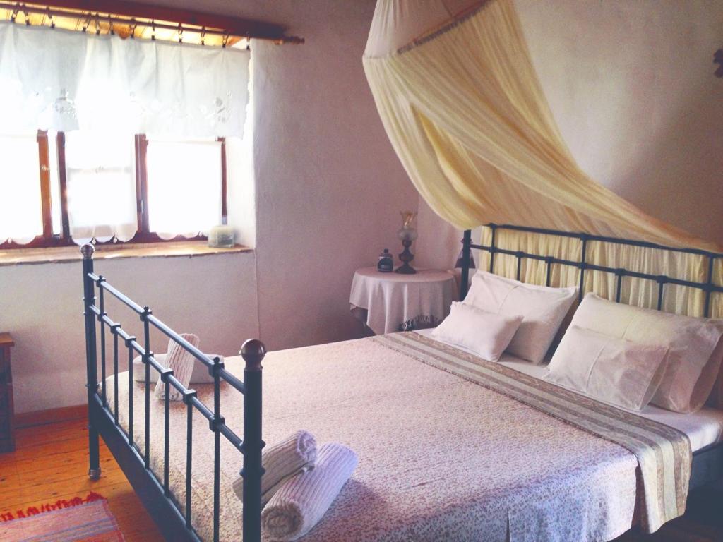 um quarto com uma cama de dossel e 2 janelas em Kaiti’s House em Arkoi