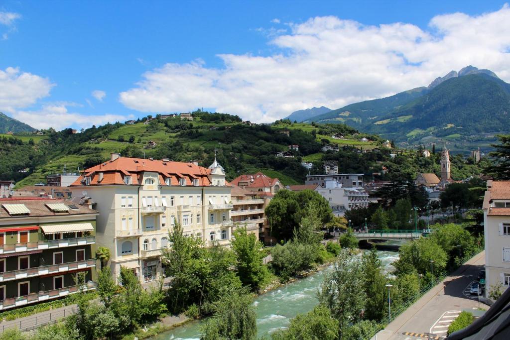 una città con un fiume e montagne sullo sfondo di Manzoni Rooms a Merano