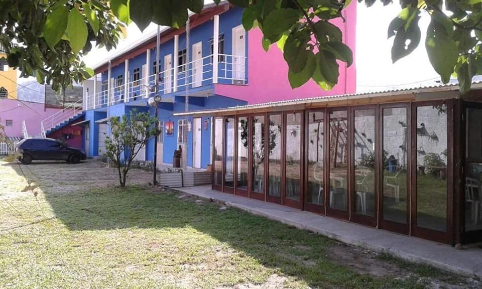 a pink and blue building with a parking lot at Pousada Flor de Liz in Angra dos Reis