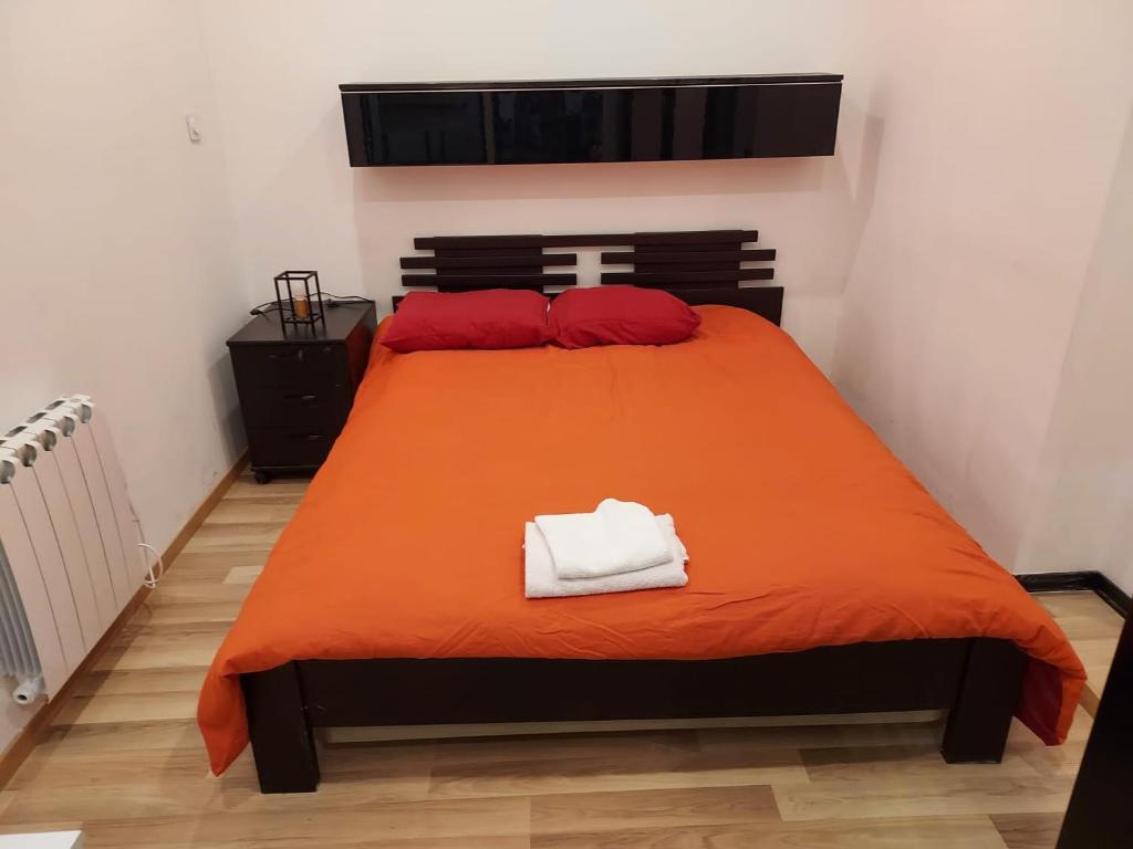 a bedroom with a bed with an orange blanket at Détente in Bischwiller