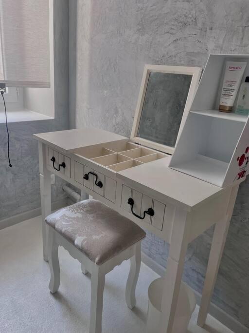 a white dressing table with a mirror and a stool at Bel appartement au centre de Branne in Branne