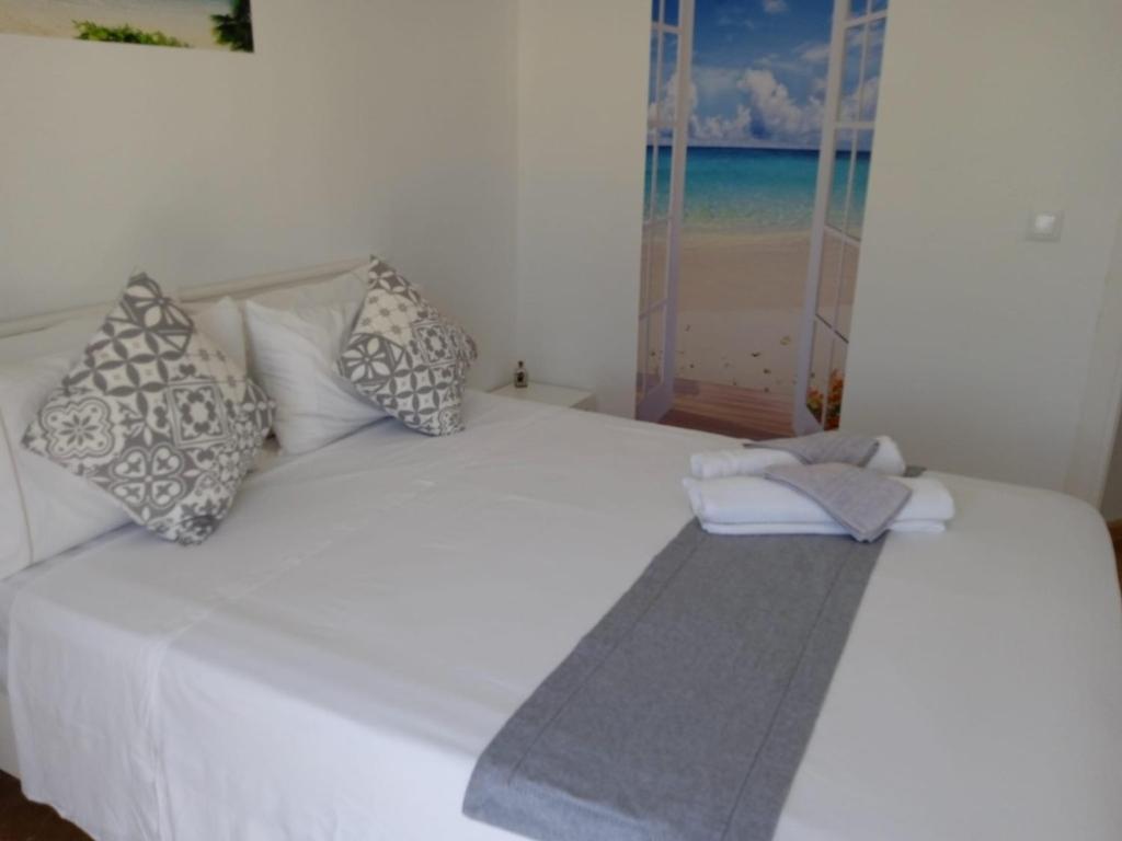 Una cama blanca con almohadas y una toalla. en Tropical Suite, en Benalmádena