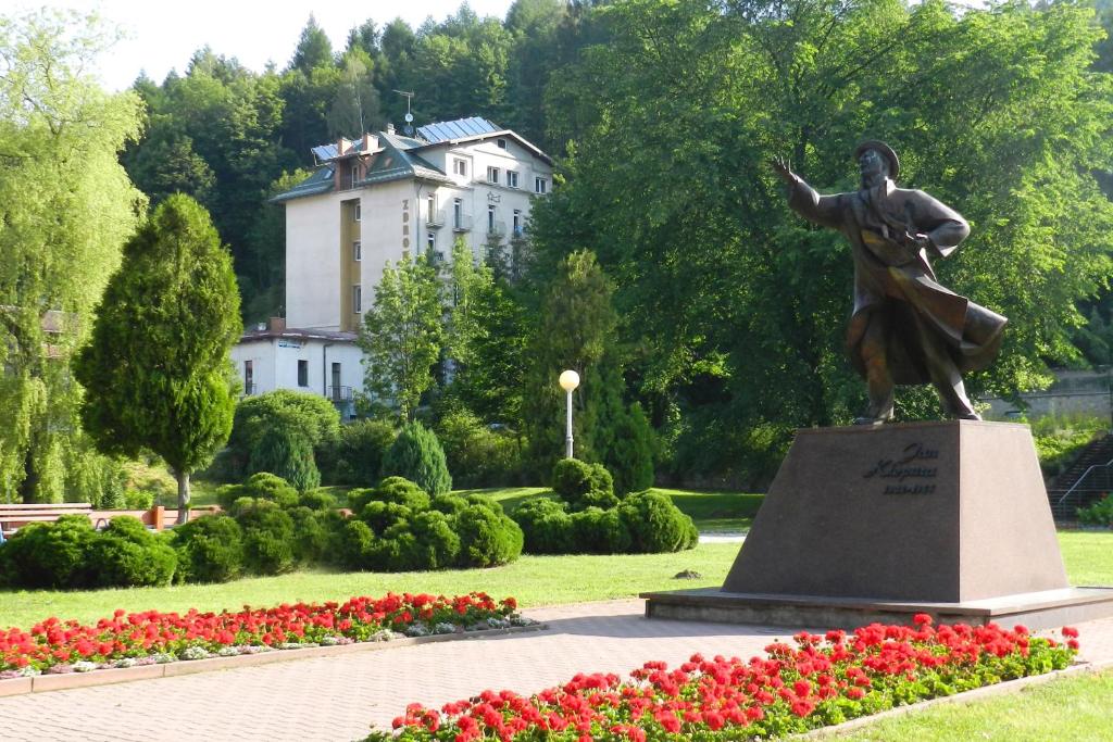 Una statua di un uomo in un parco con dei fiori di Dom Wczasowy Zdrowie a Krynica-Zdrój