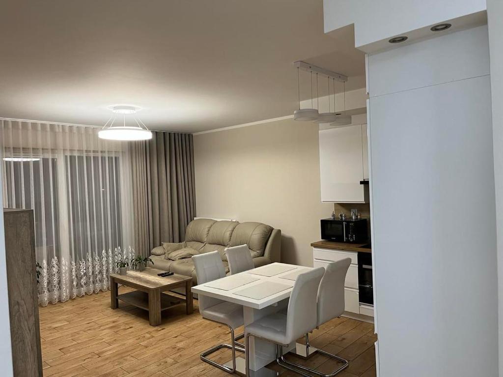 a kitchen and a living room with a table and chairs at Apartament Sielawy 21 parking free in Poznań