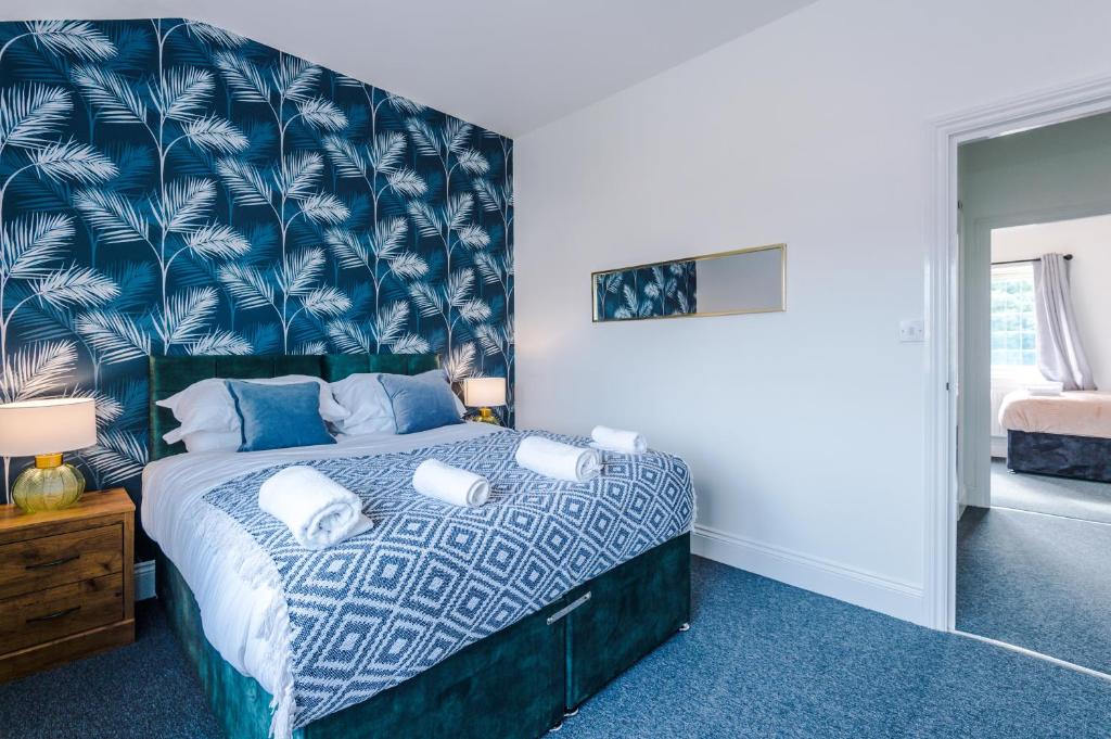 a bedroom with a bed with a blue patterned wall at Lovely 4 Bed/ Monthly Discount/ Bottle in Litherland