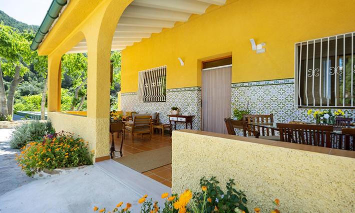 EslidaにあるParaíso Cuánticoの黄色の建物で、テーブルと椅子付きのパティオがあります。