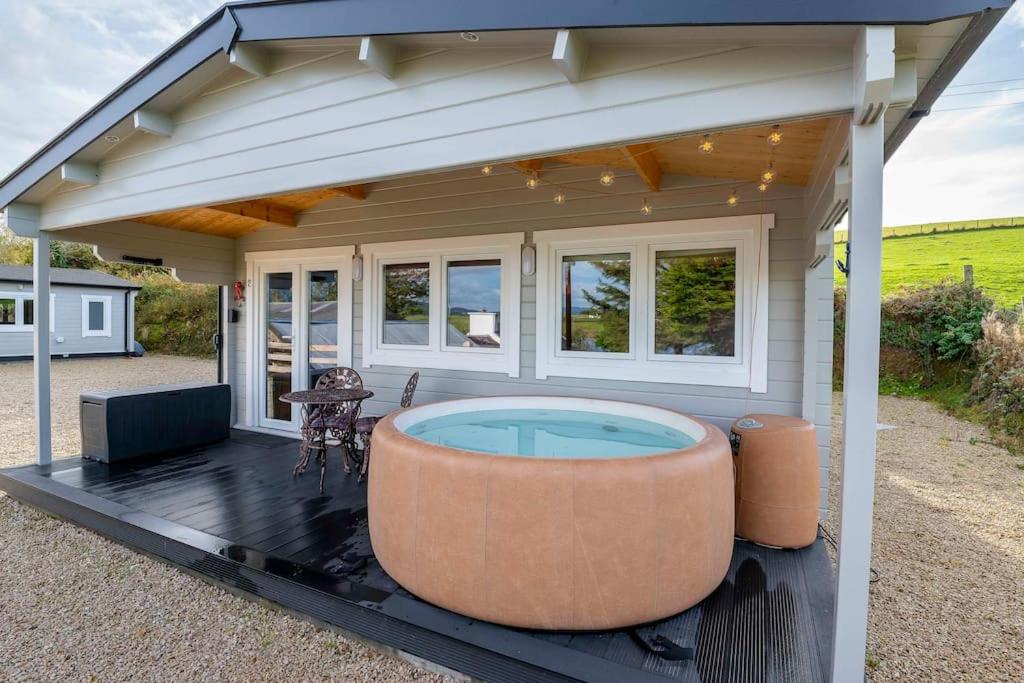 una terraza cubierta con bañera de hidromasaje en una casa en Luxury Log Cabin with Private Hot Tub & Sea Views, en Letterkenny