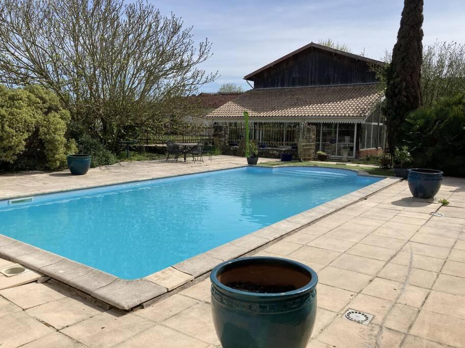une grande piscine bleue en face d'une maison dans l'établissement * Ancien domaine viticole de la Brandette *, à Gaillan-en-Médoc