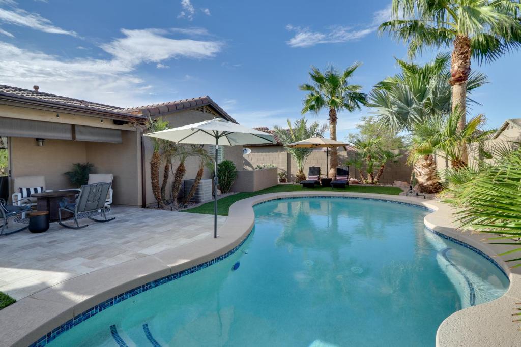a swimming pool with an umbrella and a patio with palm trees at Maricopa Retreat with Peaceful Backyard Oasis! in Maricopa