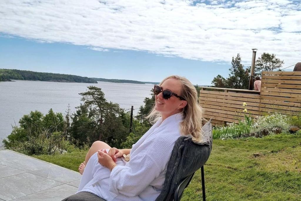 Eine Frau, die auf einem Stuhl am Wasser sitzt. in der Unterkunft Villa Stockholms skärgård 30 min från Stockholm centralt in Tyresö