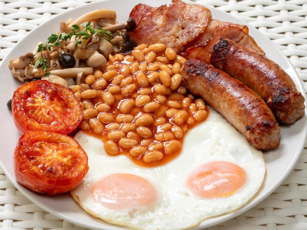 A full cooked breakfast plate includes eggs, beans, sausages, bacon, mushrooms, and tomatoes.