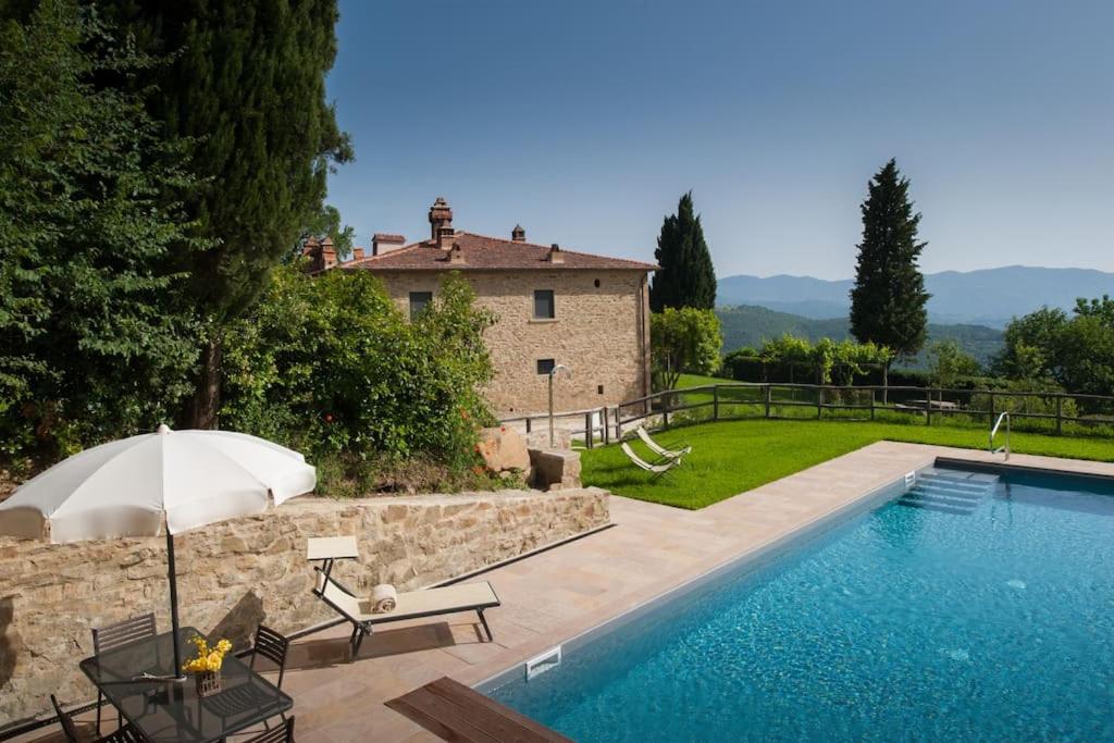 - une piscine avec un parasol et une maison dans l'établissement Villa Leopoldina - Pomaio Wines & Hospitality, à Arezzo