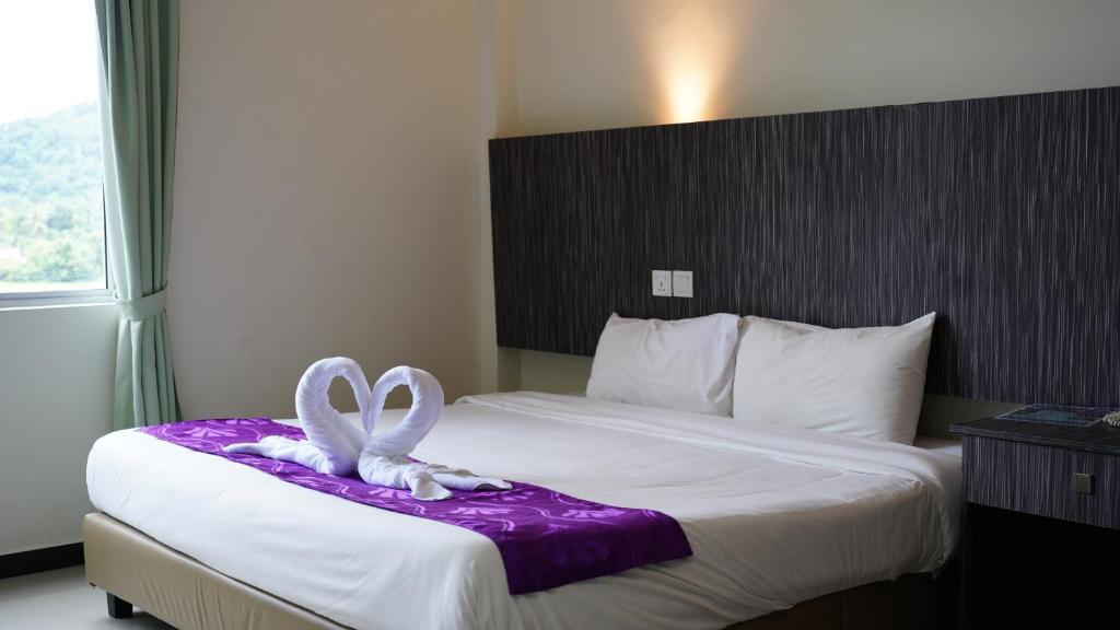 a hotel room with a bed with a bow on it at Salsa Resort Langkawi By Casa Loma in Pantai Cenang