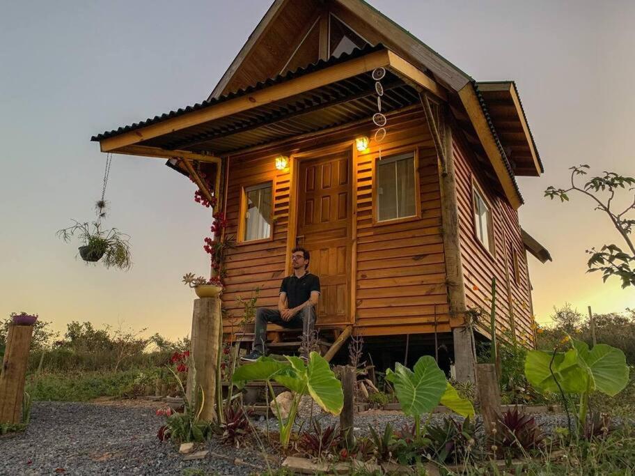 a man sitting in a chair in front of a tiny house at Chalé Vida Boa: Paz e Aconchego in Vale do Capao