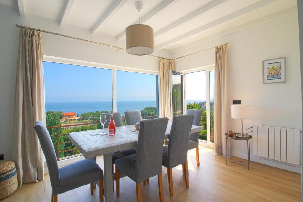 une salle à manger avec une table, des chaises et une grande fenêtre dans l'établissement Marina House, à Pechón