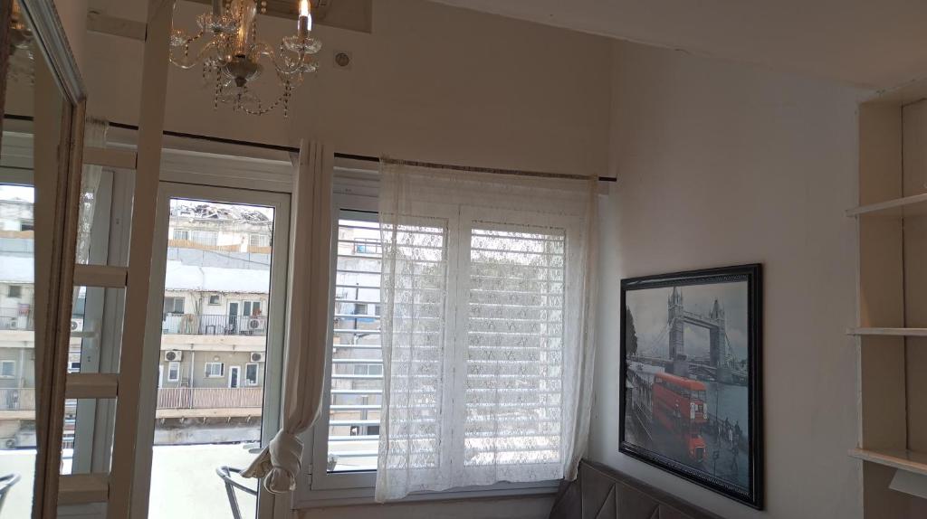 a room with two large windows and a chandelier at C.B.O. Tel Aviv 117 Allenby St. in Tel Aviv