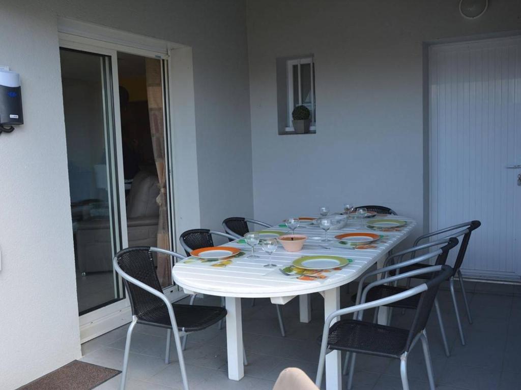 une table à manger avec des chaises et une table blanche avec des assiettes et des verres dans l'établissement Maison Saint-Gilles-Croix-de-Vie, 4 pièces, 7 personnes - FR-1-224-32, à Saint-Gilles-Croix-de-Vie