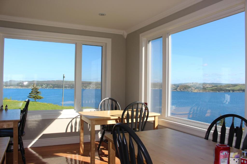 a dining room with a table and chairs and large windows at The Bayside Bed and Breakfast in Bareneed