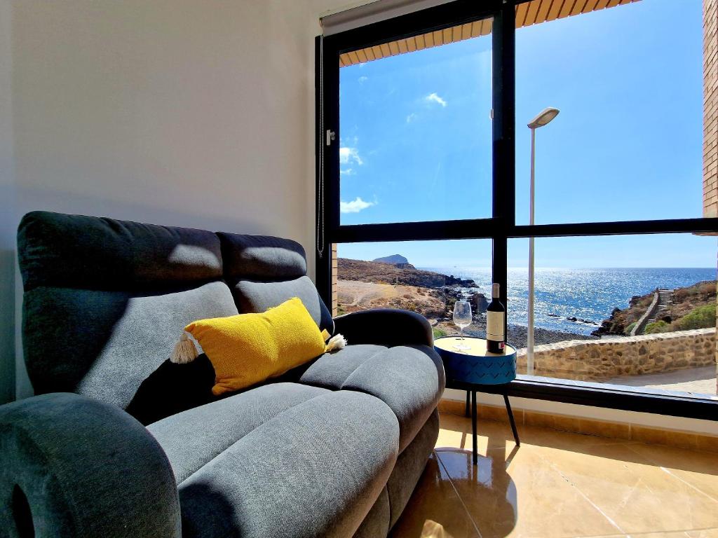 a living room with a couch and a large window at Las Rocas by the Ocean, Wifi and Sea View in Los Abrigos