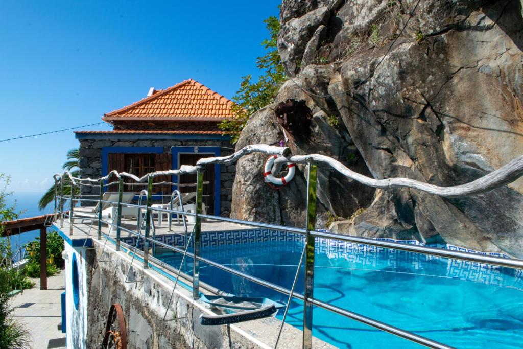 a swimming pool next to a rock wall at Unique House - Pool, Terrace & Amazing View in Ribeira Brava