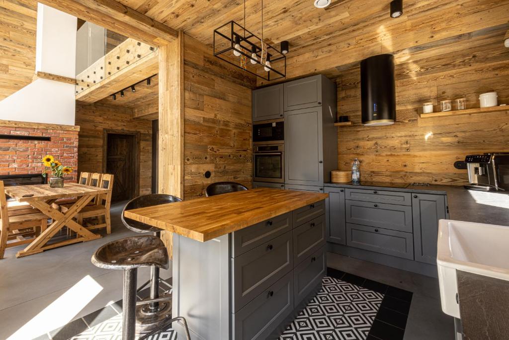 a kitchen with gray cabinets and a wooden wall at DzieńDobryMazury_Filip in Pozezdrze