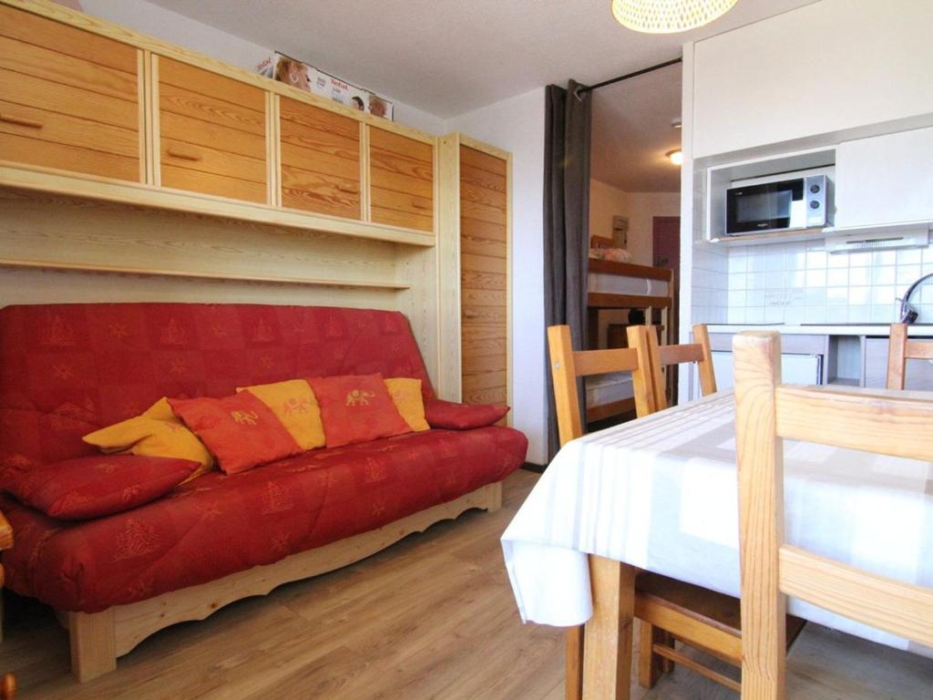 un salon avec un canapé rouge et une cuisine dans l'établissement Studio confortable pour 4 personnes à L'Alpe d'Huez avec balcon, proche commerces et pistes - FR-1-405-32, à L'Alpe-d'Huez