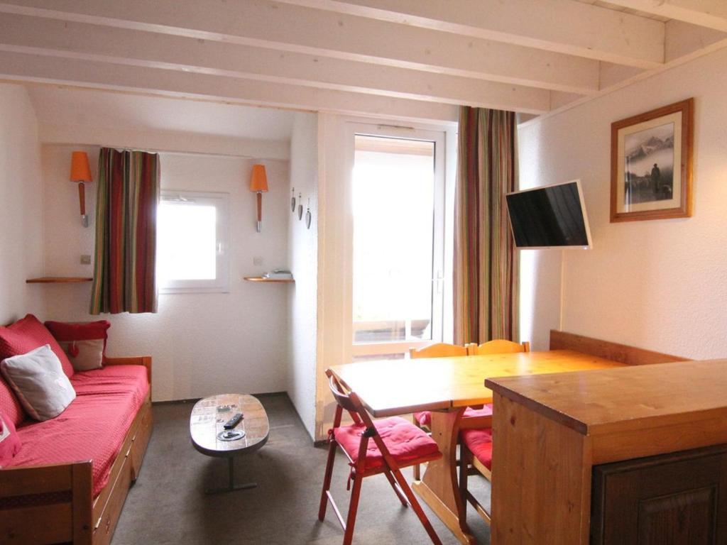 un salon avec un canapé rouge et une table dans l'établissement Charmant duplex 6 pers avec mezzanine, espace bébé, proche commerces et remontées à l'Alpe d'Huez - FR-1-405-89, à L'Alpe-d'Huez