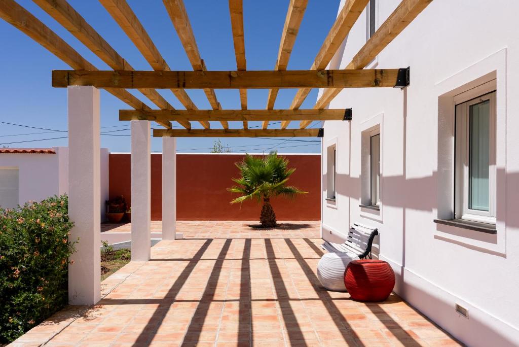 a wooden pergola on a house with a palm tree at Courela da Lameira in Reguengos de Monsaraz