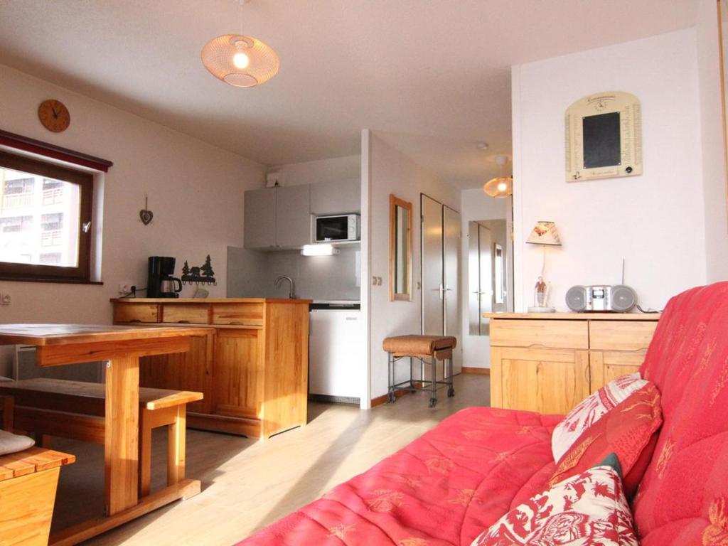 un salon avec un canapé rouge et une cuisine dans l'établissement Appartement cosy 2 pièces, balcon sud, proche remontées et commerces, parking, casier à skis, 5 pers - FR-1-405-107, à L'Alpe-d'Huez
