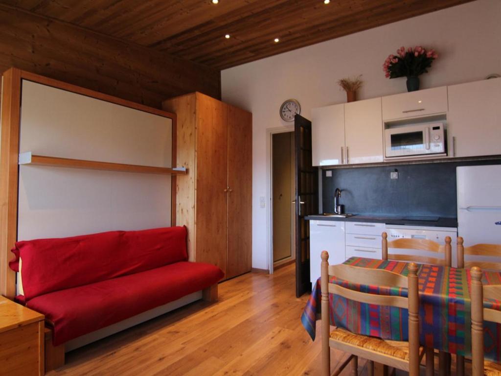 uma sala de estar com um sofá vermelho e uma cozinha em Appartement Huez, 1 pièce, 4 personnes - FR-1-405-117 em Alpe-dʼHuez