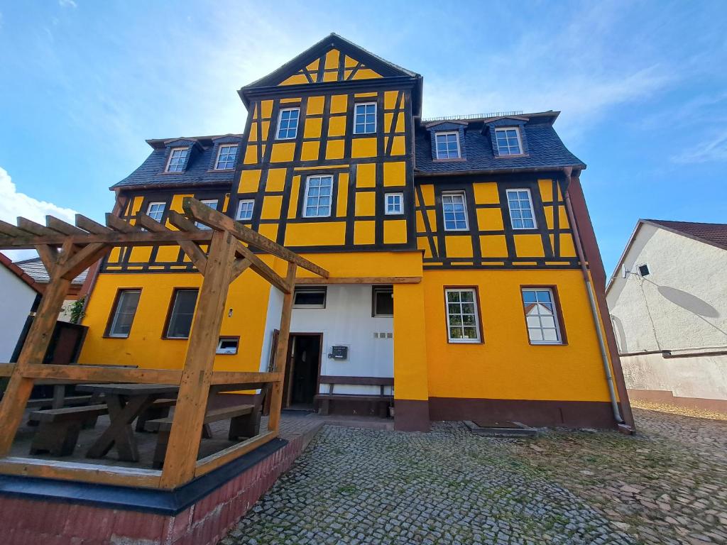 uma casa amarela com um telhado preto em Hotel zum Hirsch em Lucka