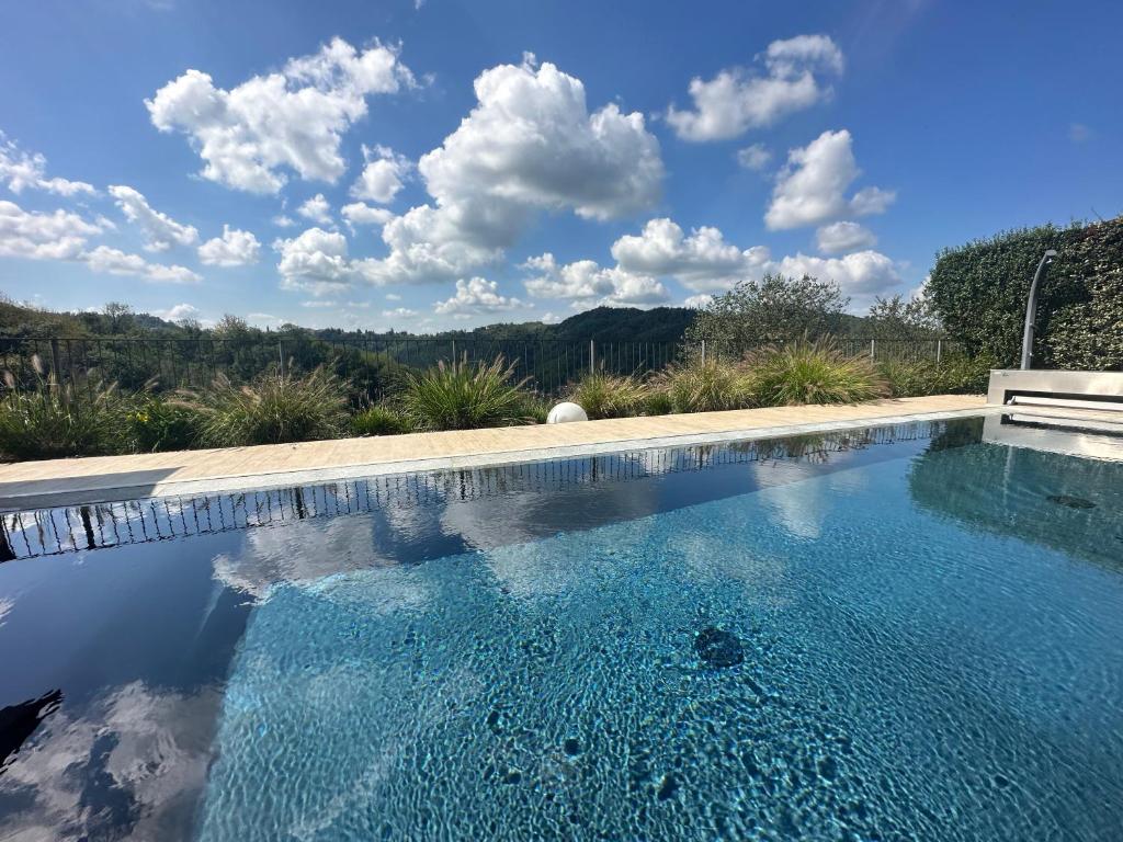 a swimming pool with blue water and clouds in the sky at Acquaementa in Brusasco