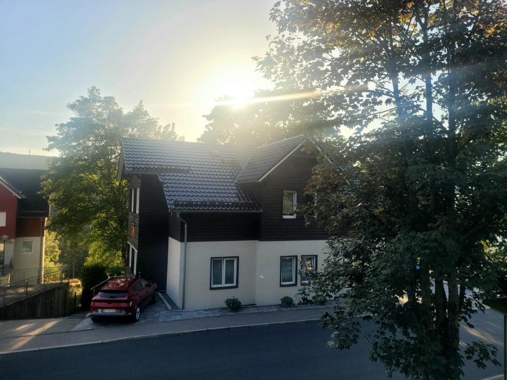 ein Haus mit einem roten Auto, das davor geparkt ist in der Unterkunft Pension & Ferienwohnung Oberhof 810 M in Oberhof