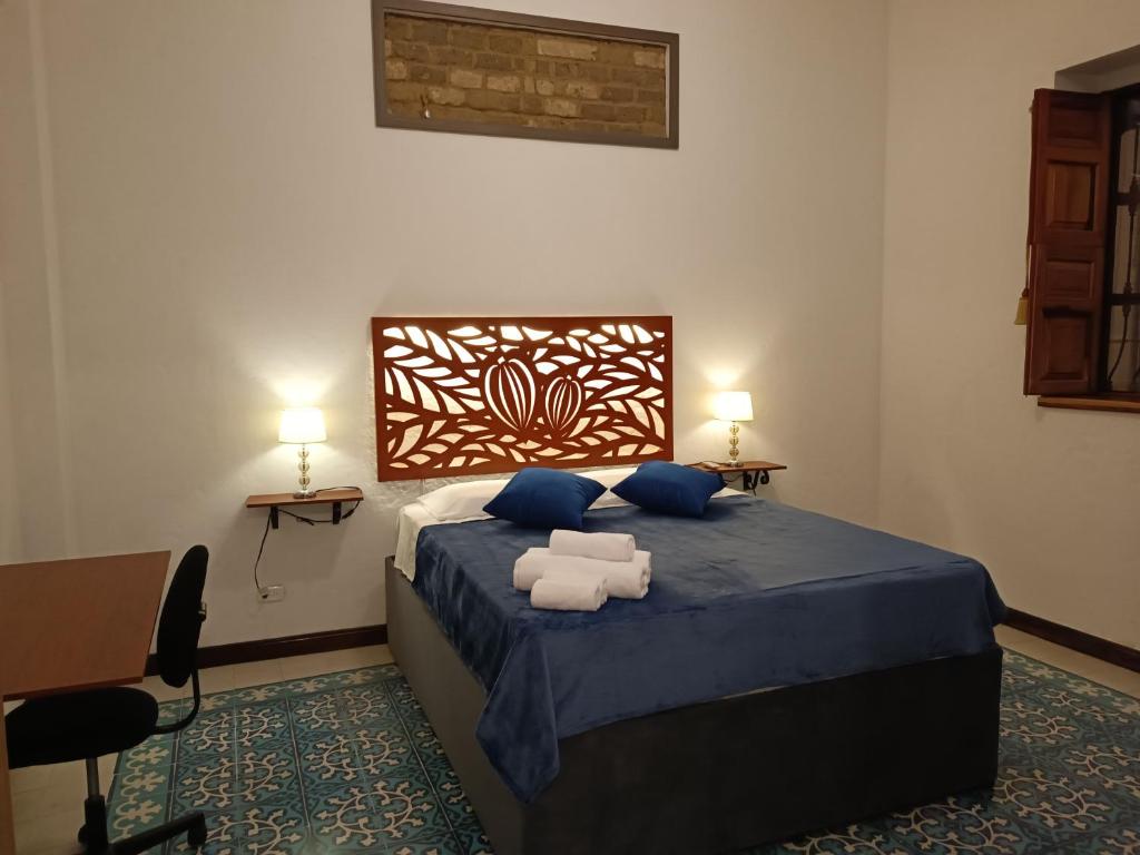 Schlafzimmer mit einem Bett mit blauer Bettwäsche und blauen Kissen in der Unterkunft Casa Carambolo in Cali