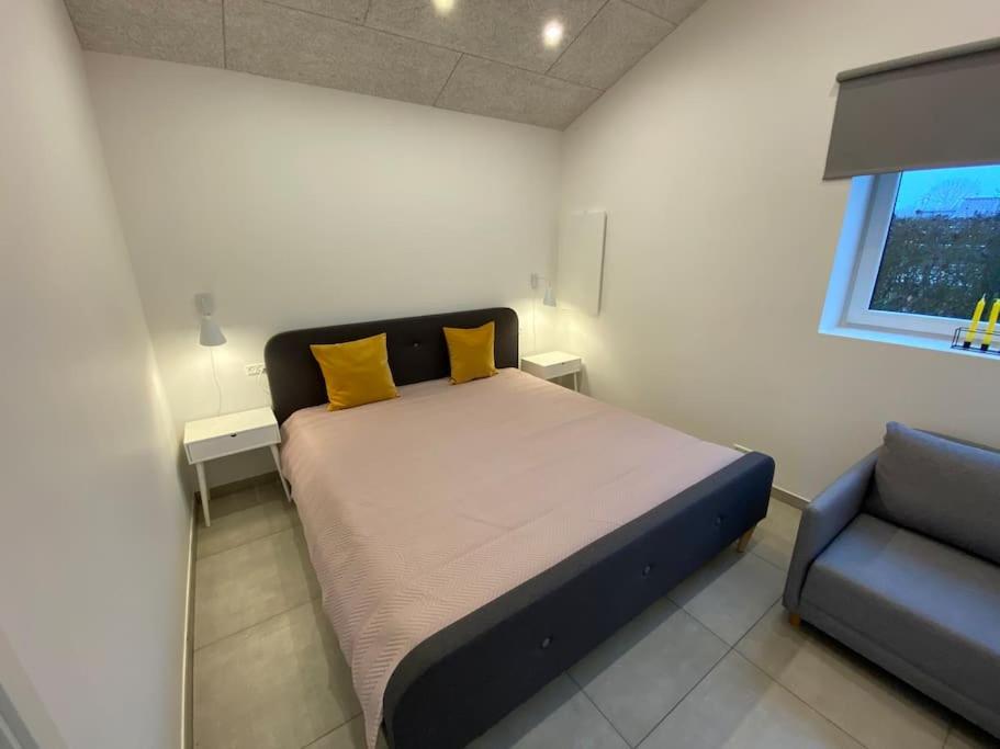um quarto com uma cama com almofadas amarelas e uma cadeira em Small Rica house in the center in Billund em Billund