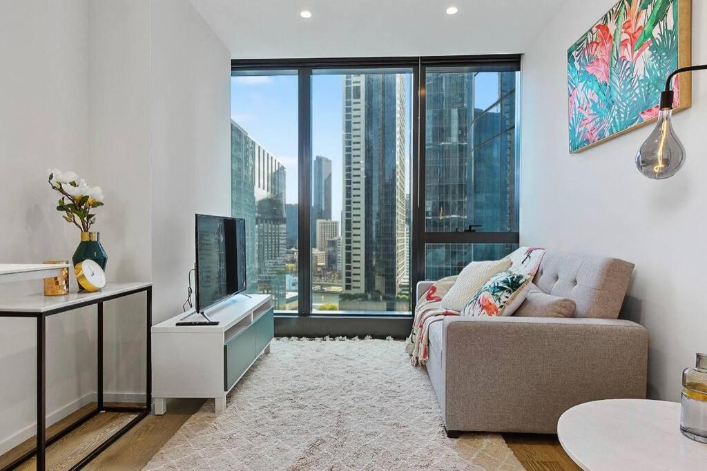 uma sala de estar com um sofá e uma grande janela em Modern 1 BR Apt on Southbank #Australia108#AU2117 em Melbourne