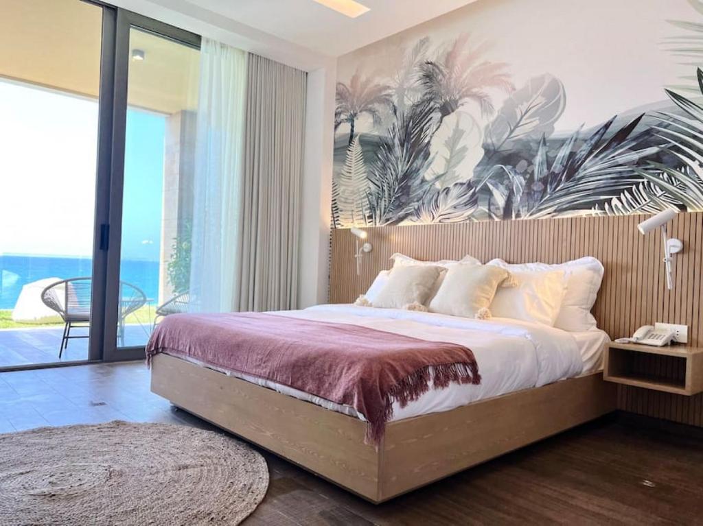 1 dormitorio con 1 cama grande y una pintura tropical en la pared en Pink Sunset Beachfront Exotic Room in Batroun, 