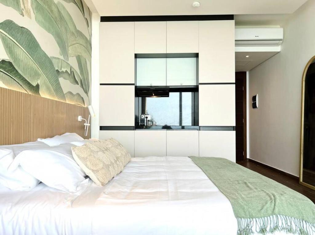 a bedroom with a large white bed and a kitchen at Banana Leaf Beachfront Exotic Room in Batroun 