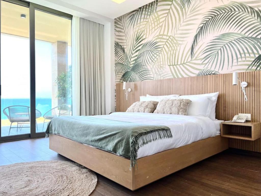 1 dormitorio con 1 cama grande y papel pintado tropical en Wild Areca Beachfront Exotic Room in Batroun, 