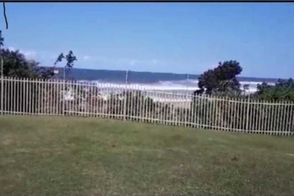 a fence in a yard with the ocean behind it at Off-shore Guest house in Margate