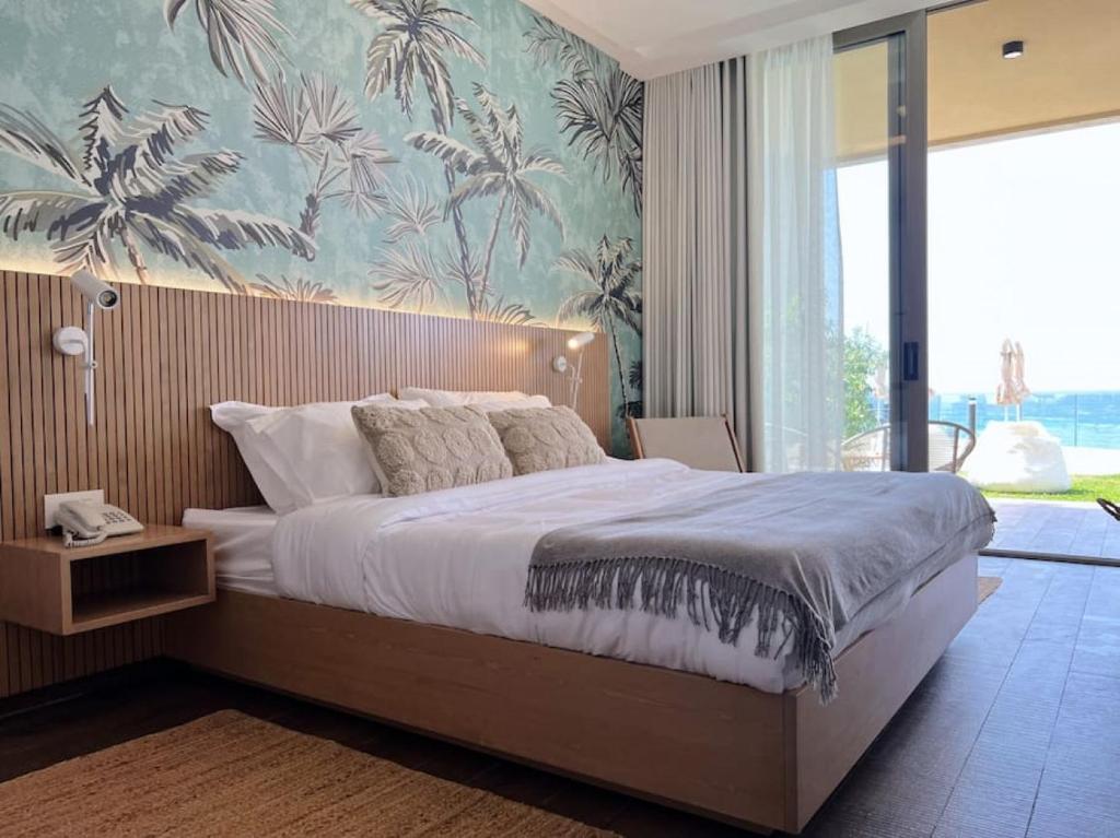 ein Schlafzimmer mit einem großen Bett und einer tropischen Tapete in der Unterkunft Palm Paradise Beachfront Exotic Room in Batroun 